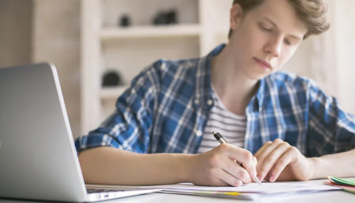 male-teenager-laptop-writing-notes